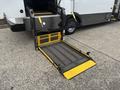 A wheelchair ramp extended from the side of a 2020 Chevrolet Express with yellow markings and a textured surface for traction