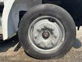 A close-up of a truck tire mounted on a silver wheel featuring multiple bolt holes and a red center cap