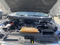 The image shows the open hood of a 2015 Ford F-150 revealing the engine compartment with components like the battery and coolant reservoir visible
