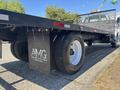 A 2004 Ford F-750 flatbed truck with a black body and large wheels parked on a concrete surface