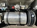 A silver fuel tank mounted on a truck with various connections and fittings visible on the surface