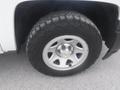 A close-up of a tire and wheel from a 2015 Chevrolet Silverado 1500 showing a silver wheel with a Chevrolet emblem and heavy tread on the tire