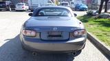 A gray 2007 Mazda Miata viewed from the rear displaying its round taillights and an empty license plate holder