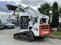 A 2017 Bobcat T740 compact track loader with a white and orange body and a bucket attachment is shown from the side with the tracks visible