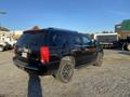 A black 2007 Cadillac Escalade with off-road tires parked on gravel, showcasing its distinct luxury SUV design and prominent rear features