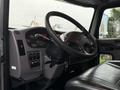 A 2020 Peterbilt 330 interior featuring a black steering wheel dashboard with various controls and a large black seat