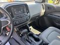 The interior of a 2017 Chevrolet Colorado featuring a dashboard with a touchscreen display center console gear shifter and seating in a light gray fabric