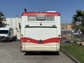 A 2016 Grande West Vicinity bus viewed from the rear featuring a red and white color scheme with taillights and a large rear window