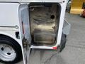 A 2015 Ford F-550 service truck with an open compartment door revealing a metal storage area with a mesh bottom