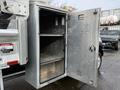 An open aluminum storage cabinet mounted on a truck showing two shelves inside