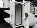 A 2020 International MV607 truck with an open side compartment featuring two shelves and a circular latch inside