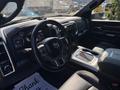 The interior of a 2018 RAM 3500 featuring a black steering wheel a digital instrument panel and leather seats with a console displaying storage compartments and cup holders