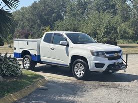 White 2017 Chevrolet Colorado with a blue and silver utility bed featuring storage compartments and a front-mounted winch