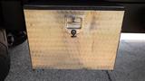 A metal storage box with a textured surface and a lock on the front, mounted on a truck