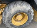 Close-up of a large, worn tire belonging to a 2012 John Deere 310SJ showcasing deep tread and a yellow rim