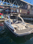 A 2013 Larson 238 boat with a sleek white hull and spacious seating is docked at a marina, showcasing its modern design and comfortable layout
