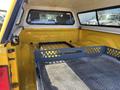 The interior of a 2015 RAM 1500 truck bed with a yellow lining and a black metal bed divider visible in the foreground