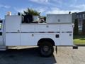 A 2009 Ford F-550 with a service body featuring multiple storage compartments and equipment such as a light bar and a spool on the roof