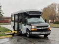 A 2019 Chevrolet Express shuttle bus with an extended front and a wheelchair lift lowered at the side entrance