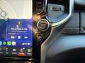 A dashboard display featuring a touchscreen with music controls and buttons for navigation and settings in a 2023 RAM 3500