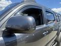 A 2010 Toyota Tacoma with a black exterior and side mirror reflecting light