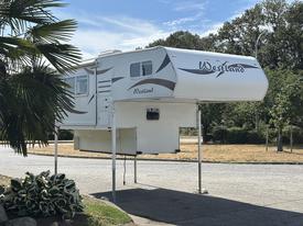A 2018 Westland Travelaire truck camper elevated on supports with a sleek exterior design including the brand name Westland prominently displayed