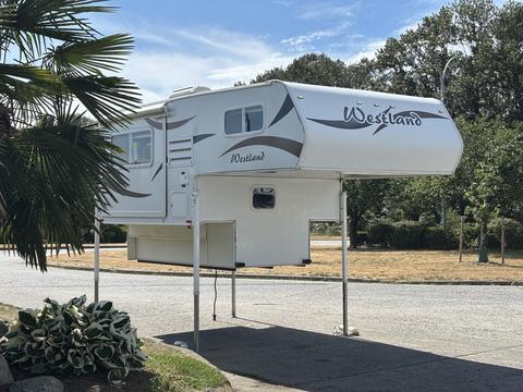 A 2018 Westland Travelaire truck camper elevated on supports with a sleek exterior design including the brand name Westland prominently displayed