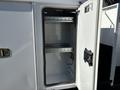 An open storage compartment on a 2013 International 7500 with empty shelves and a door that has a handle and latch system