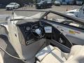 Interior view of a 2013 Larson 238 boat featuring a steering wheel multiple gauges and a Lowrance fish finder display on the dashboard