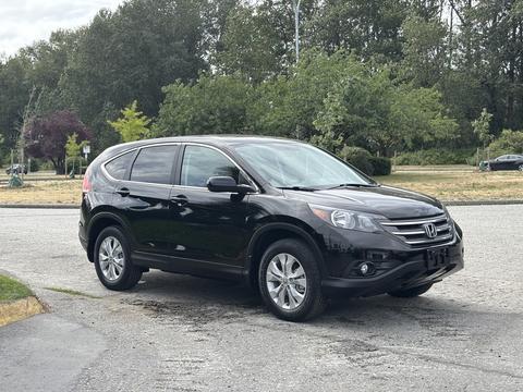 A black 2014 Honda CR-V parked on a roadway with a sleek design showcasing its headlights and alloy wheels
