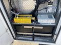A yellow inverter is installed in a compartment alongside a power supply unit and two black batteries inside a 2011 Chevrolet Express van
