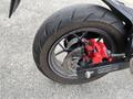 Close-up of a rear wheel of a 2018 Honda Grom featuring a black tire and a red brake caliper with disc brake visible