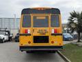 A yellow 2022 Freightliner B2 school bus viewed from the rear displaying a sign that reads Do Not Pass When Red Lights Flashing and an emergency door label