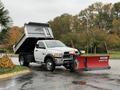 A 2012 Dodge Ram 5500 with a dump bed raised and a snow plow attached at the front