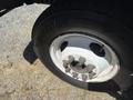 A close-up of a white steel wheel with rusted lug nuts and a Bridgestone tire mounted on it
