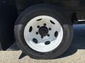Close-up of a white wheel rim with a black tire featuring multiple lug nuts and the brand name visible on the sidewall