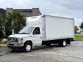 A 2022 Ford E-450 box truck with a white cargo area and black wheels parked at an angle