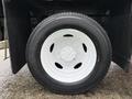 A close-up of a white wheel with a silver hubcap mounted on a black tire of a 2022 Ford F-550