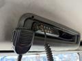 A mounted communication radio with a coiled microphone attached inside a vehicle cab