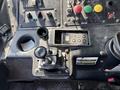 A close-up of the dashboard of a 2011 Autocar Xpeditor featuring a gear shift lever multiple buttons and control switches with colored buttons