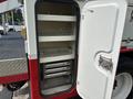A 2012 International 7300 Workstar truck with an open storage compartment featuring shelves and sliding drawers