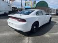A white 2017 Dodge Charger with a rear spoiler and black wheels parked in a lot, showcasing its sporty design and sleek lines