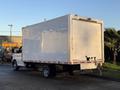 A 2015 GMC Savana box truck with a white cargo area and a dark chassis parked on a street