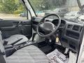 Interior view of a 2010 Suzuki Carry showing the driver's seat steering wheel gear shift and dashboard with controls and a thank you mat on the floor