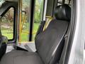 The interior of a 2015 Chevrolet Express showing a black driver's seat with a seatbelt and armrest