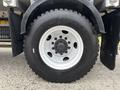 A black tire mounted on a white rim featuring six lug bolts with a central cap visible on a heavy-duty vehicle