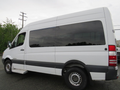 A 2009 Dodge Sprinter Van in white with black accents and large tinted windows parked at an angle showcasing its side profile and sliding door