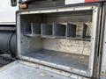 A metallic storage compartment of a 2010 International 4300 with six metal shelves inside arranged neatly