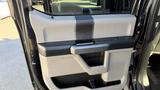 A close-up view of the interior door panel of a 2016 Ford F-150 featuring a textured gray surface black trim and a handle