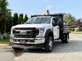A 2022 Ford F-550 truck with a white exterior and a flatbed cargo area parked on a driveway